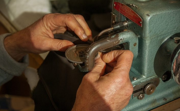 Close up on mans hands at work with sewing machine
